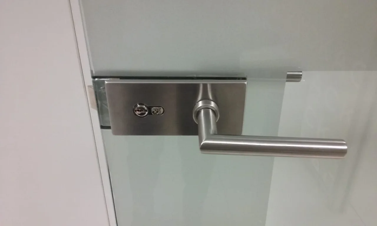 Manilla sobre placa y cerradura en una puerta acristalada