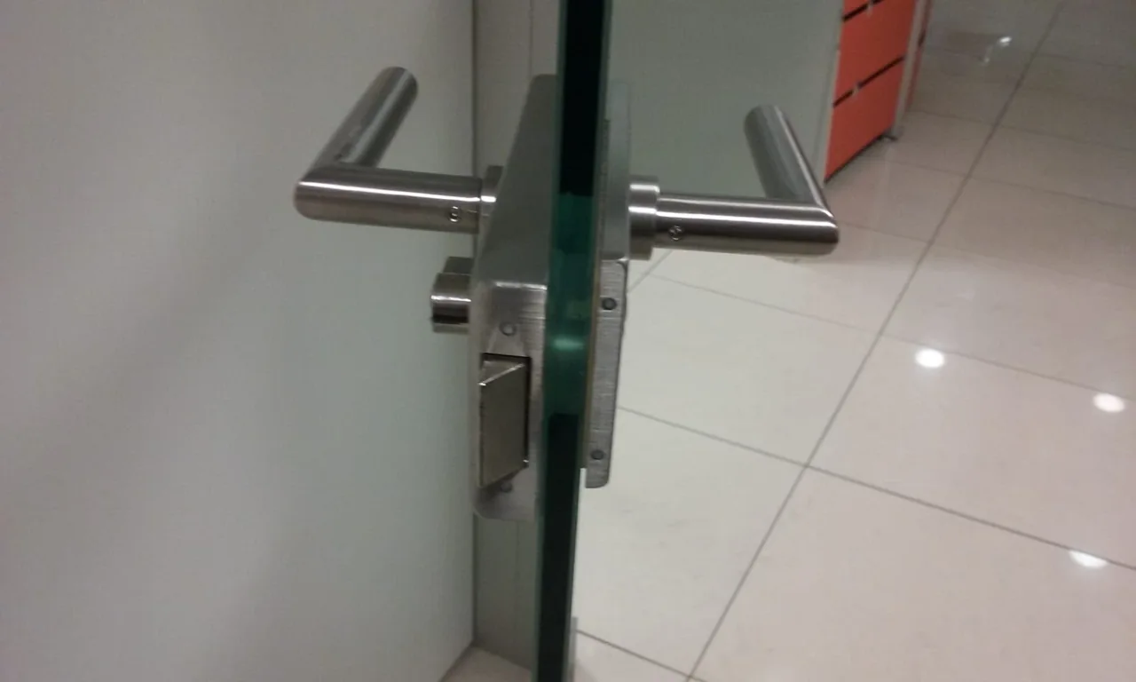 Manilla y cerradura en el canto de una puerta acristalada